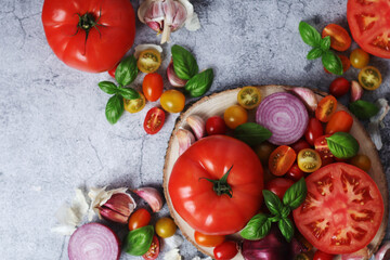 Flat lay composition of different tomatoes, onion, basil and garlic	