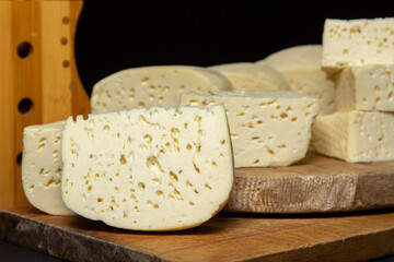 White cheese on a black background. Homemade white cheese on a wooden board. Traditional cuisine