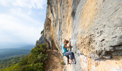 Fototapeta premium A strong girl climbs a rock