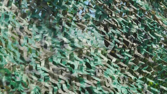 Military green camouflage net masking and covering a secret object. Camera panning