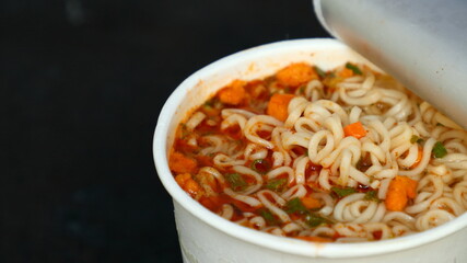 Instant noodles in white cups, unbranded. on a black wooden background