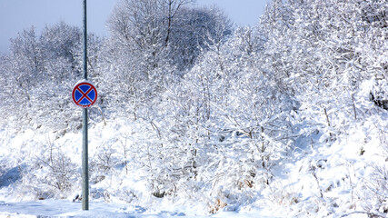 No stopping road sign in the wood in winter. Snow covered warning sign outdoors.