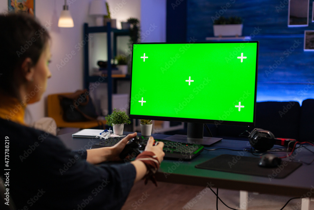Poster woman looking at horizontal green screen on monitor, playing video games with controller. gamer usin