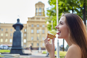 attractive girl with long hair holds a cake in her hands and licks it with her tongue. photo shoot in the city