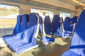 Interior of a passenger train with empty blue seats.