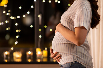 christmas, pregnancy and people concept - close up of pregnant woman at window at home