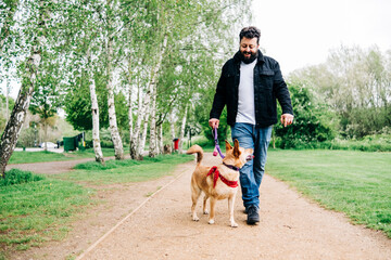 Smiling man walking with dog on footpath at park