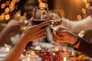 holidays, drinks and celebration concept - close up of hands toasting wine glasses at dinner party...