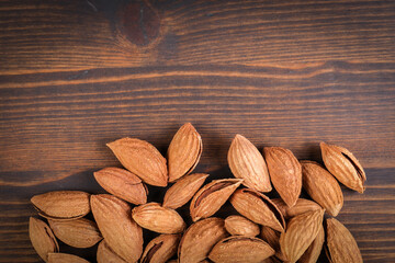 Almond nuts in a pile on a wooden texture background. Copy space