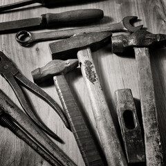 old hand tools - hammers, wrench, chisel, pliers on a wooden background