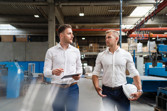 Male professionals discussing while walking in factory