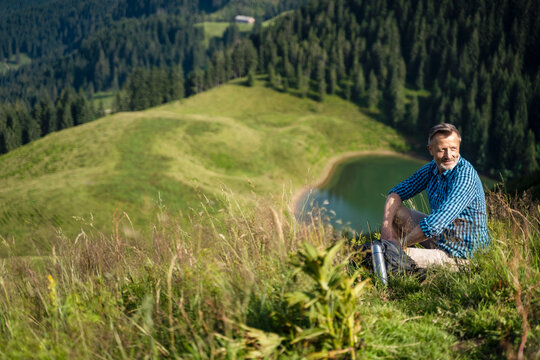 Smiling male hiker resting while sitting on mountain