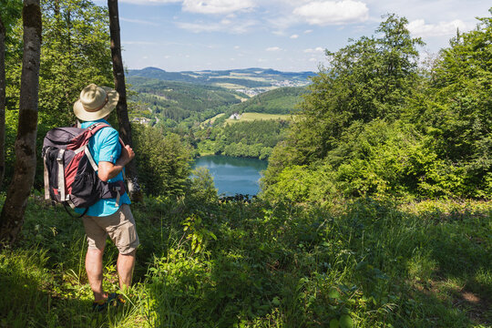 Senior hiker admiring landscape surrounding Gemundener Maar lake