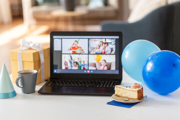 technology and online party concept - piece of birthday cake on plate and laptop computer with video call on screen at home