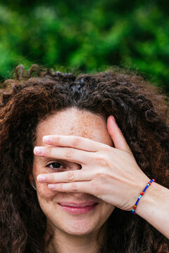 Smiling Curly Haired Woman Peeking Through Fingers