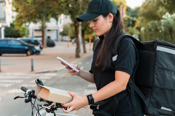 Young female delivery person scanning package with smart phone