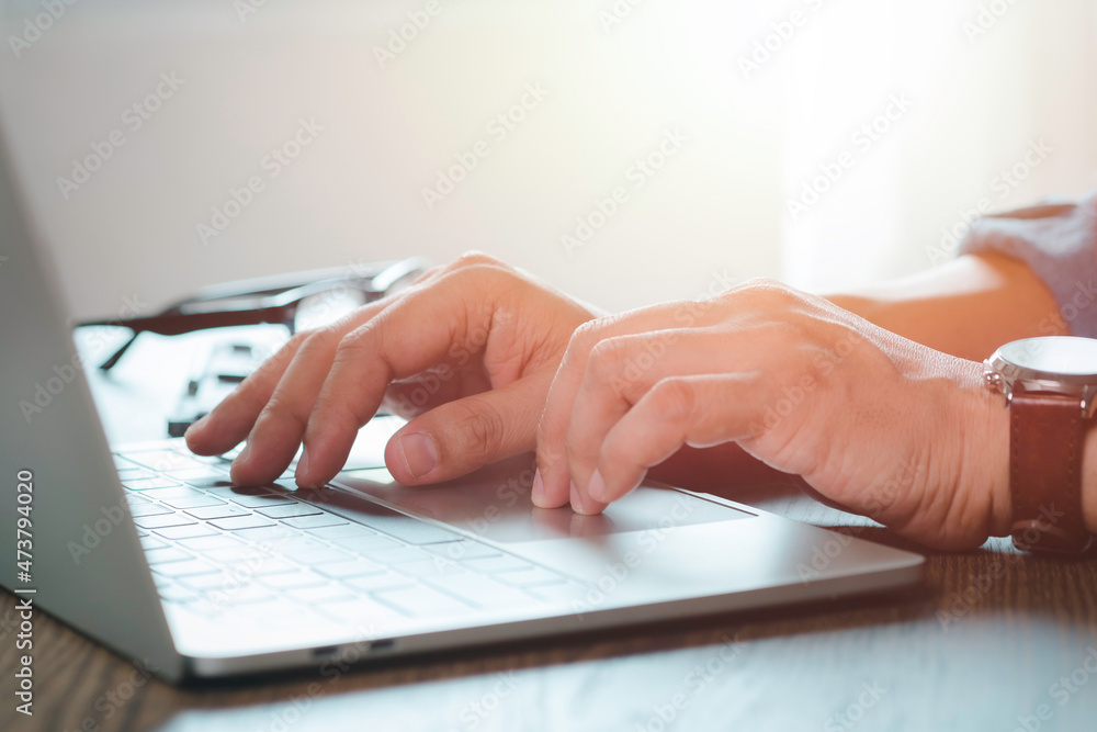 Poster close-up of man hands using and typing keyboard of laptop computer on office desk. workspace, busine