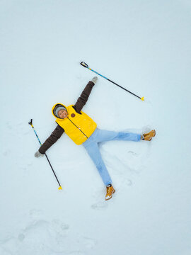 Russia, Aerial view of adult woman making snow angel with ski poles in hands