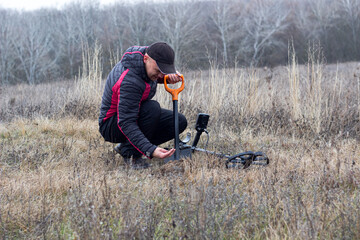 man with a metal detector and a shovel looks at the find