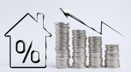 Mortgage concept. Many stacked silver coins and house model on light background