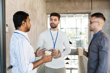 Obraz premium business, people and corporate concept - businessmen or male colleagues with name tags drinking takeaway coffee at office