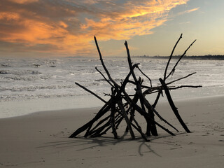 Tipi aus Treibholz am Meer vor dramatischem Himmel