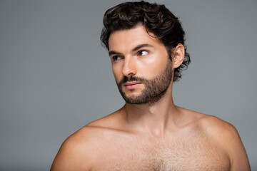 muscular and bearded man looking away isolated on grey