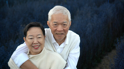 Fototapeta premium Asian retired senior couple celebrating winter in beautiful blue magical flower field