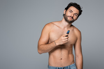 Fototapeta na wymiar young shirtless man holding electric razor isolated on grey