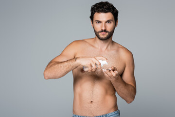 shirtless man applying toner on cotton pad and looking at camera isolated on grey