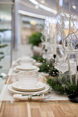 Festive christmas table setting with white plates and candles and holiday season decor.