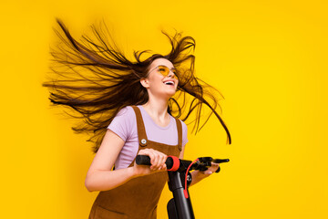 Portrait of attractive cheerful dreamy girl riding scooter air blowing having fun good mood...