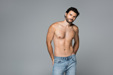 good-looking and shirtless man in jeans looking at camera isolated on grey