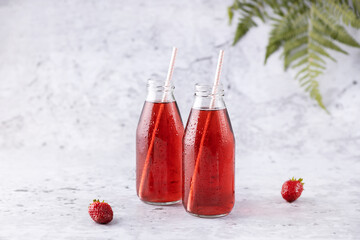 two bottles of homemade strawberry drink and fresh berries on a gray background © Irina