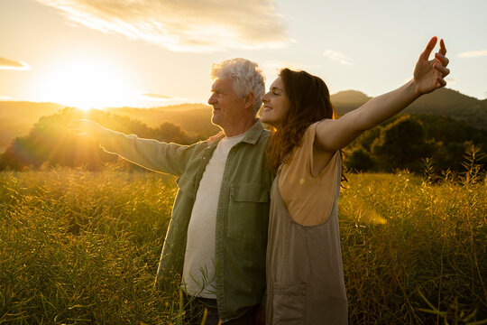 Smiling man and woman stretching hand while standing in field