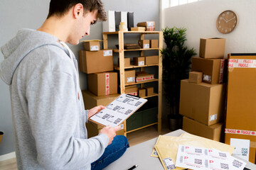 Male entrepreneur examining QR codes on clipboard at office 