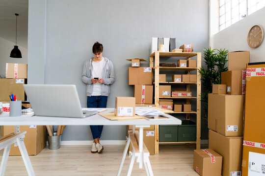 Male professional using mobile phone in front of wall at office
