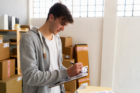 Male professional writing on clipboard in warehouse