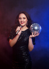 Naklejka premium Party happy woman wearing black dress with disco ball and microphone
