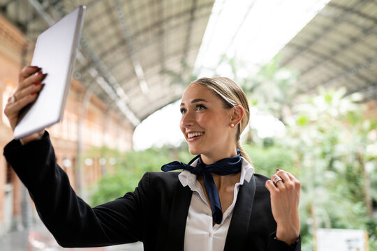 Blond female flight attendant taking selfie on digital tablet in garden