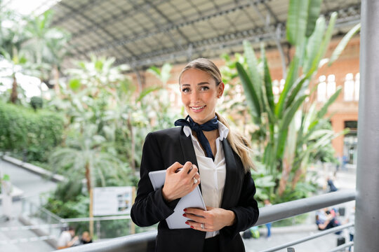 Confident air stewardess with digital tablet standing in garden