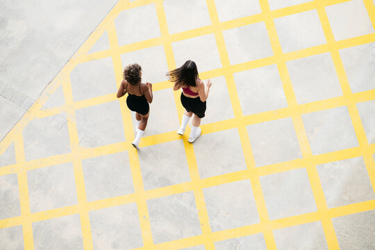 Multi-ethnic female friends jogging together on footpath