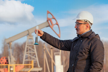 An oil geologist with a tablet next to an oil pump. Close up