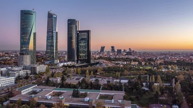 Backwards reveal of modern high rise buildings in business district. Aerial hyperlapse footage of at dusk. Madrid, Spain