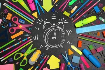 Different stationery and drawn alarm clock on blackboard surface, flat lay. Time to school