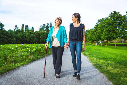 Smiling grandmother holding hand of granddaughter while walking on road