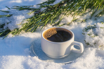 White cup of hot coffee on a bed of snow and white background, close up