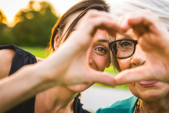 Granddaughter and grandmother making heart with hand at park