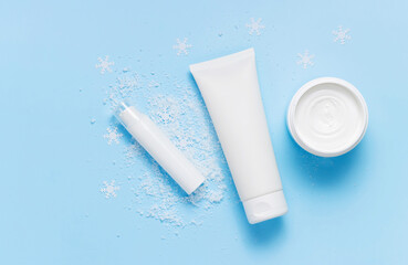 Top view bottles with face cream, mask and under eye serum on the snow, winter skin care
