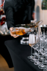 a man's hand pours champagne into a glass